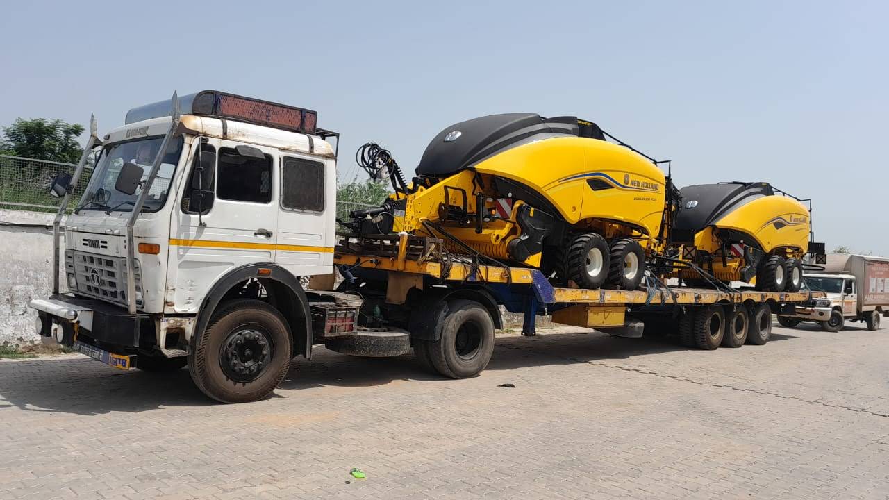 A trailer carrying yellow agricultural machinery, secured for an over-dimensional move